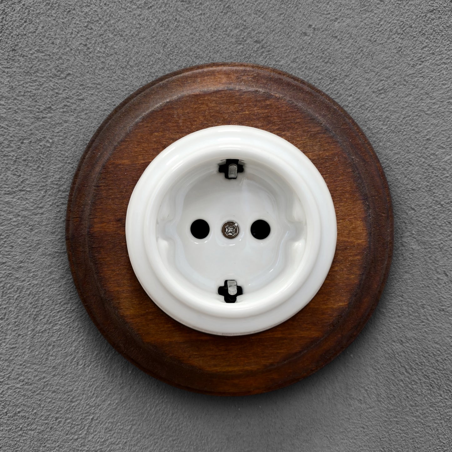 Single SCHUKO porcelain socket with dark wooden frame, white, flush-mounted, front view