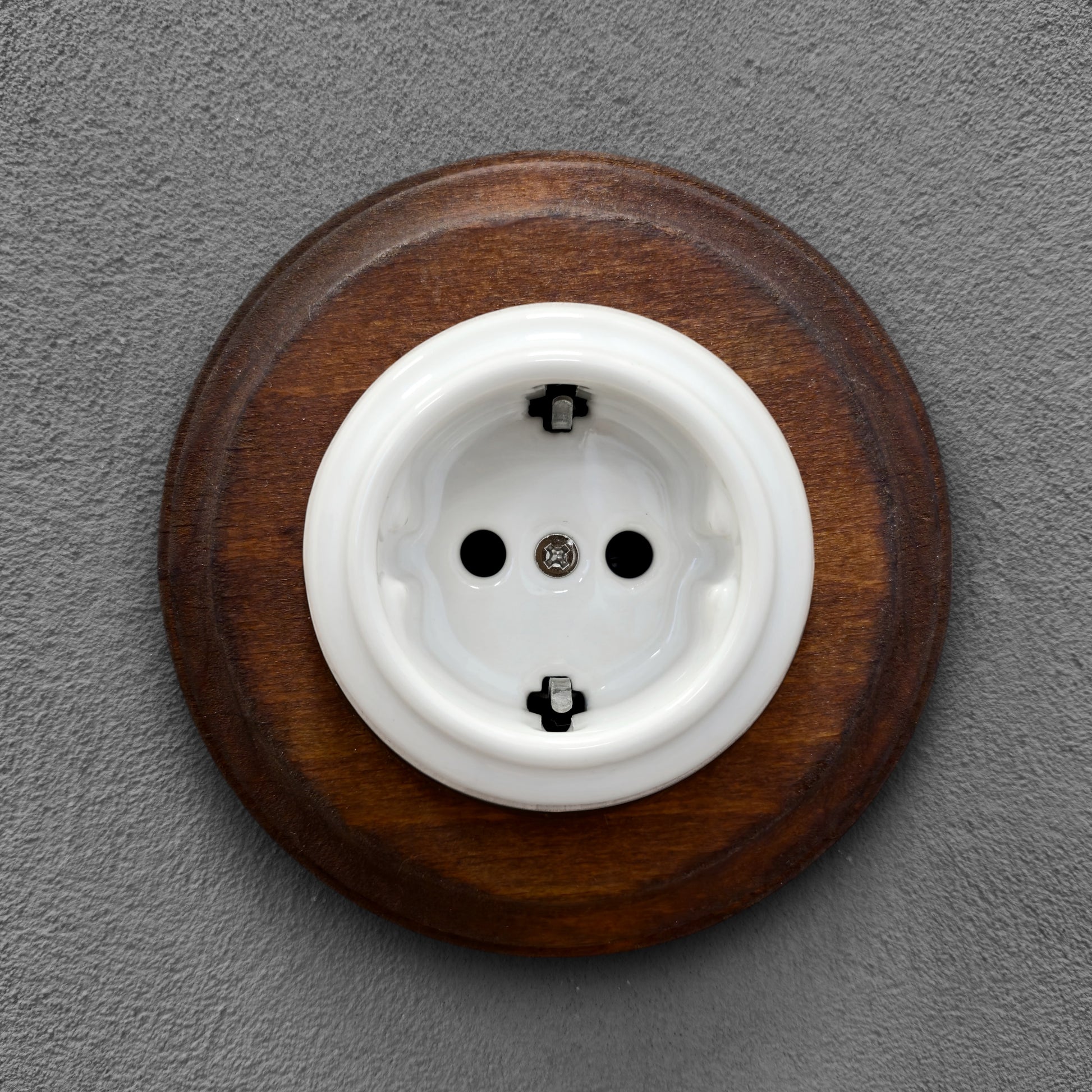 Single SCHUKO porcelain socket with dark wooden frame, white, flush-mounted, front view