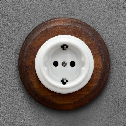 Single SCHUKO porcelain socket with dark wooden frame, white, flush-mounted, front view