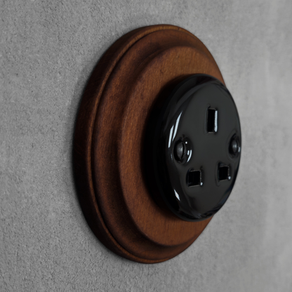 Black porcelain UK Plug Socket with dark wood frame, flush-mounted, side