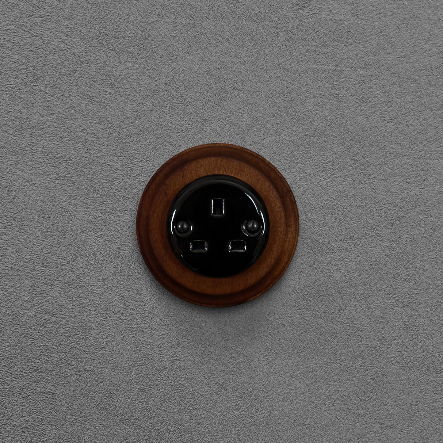 Black porcelain UK Plug Socket with dark wood frame, flush-mounted