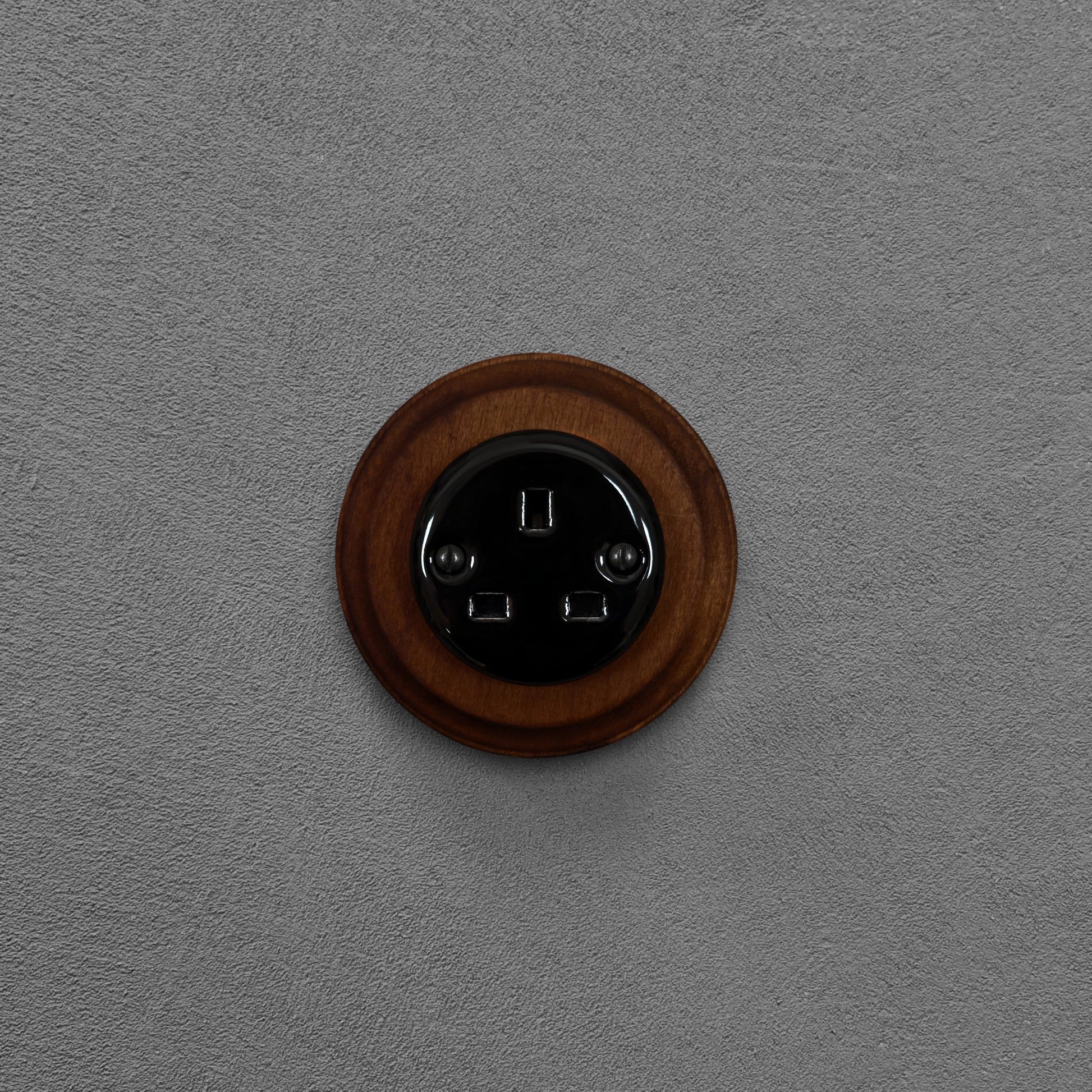 Black porcelain UK Plug Socket with dark wood frame, flush-mounted